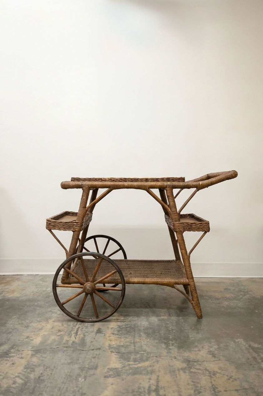 Antique wicker and rattan tea cart with large spoke wheels and multiple serving tiers