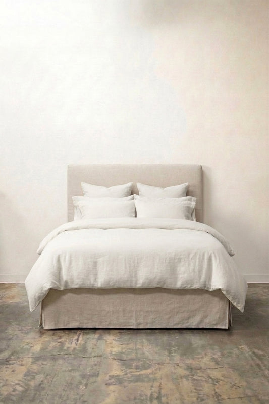 Upholstered linen bed with clean headboard and box pleat skirt in natural linen